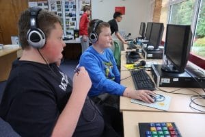 Two members of our radio group work on their podcast with headphones at the computers